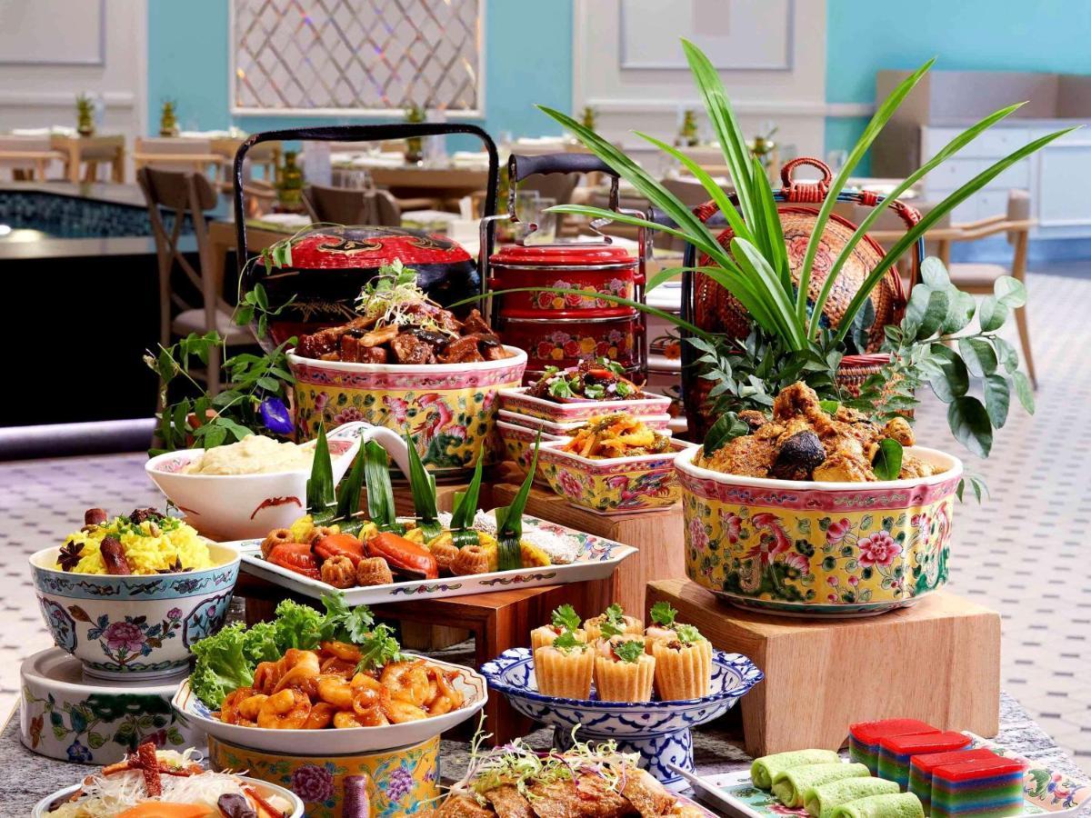 Paradox Singapore Merchant Court At Clarke Quay المظهر الخارجي الصورة The photo displays a vibrant and lavish spread of various dishes arranged on a table. There are colorful bowls filled with different types of food, including rice, noodles, and an assortment of meats and vegetables. Some dishes are garnished with fre