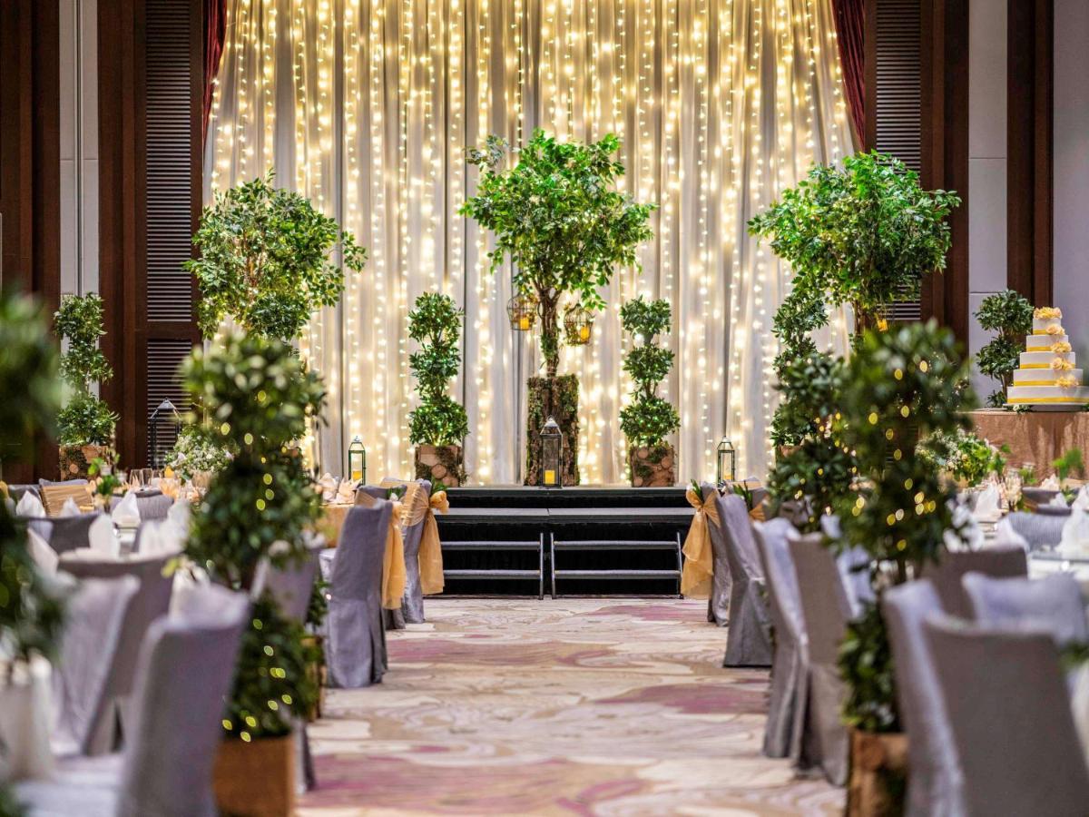 Paradox Singapore Merchant Court At Clarke Quay المظهر الخارجي الصورة The photo shows a beautifully decorated event space, likely set up for a wedding or a formal gathering. The scene features:

- A backdrop of draped fabric embellished with twinkling fairy lights, creating a romantic ambiance.
- Several potted greener