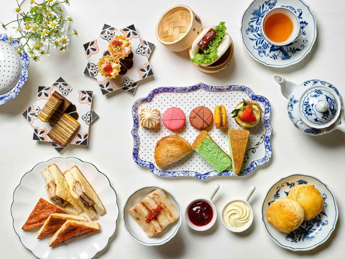 Paradox Singapore Merchant Court At Clarke Quay المظهر الخارجي الصورة The photo displays a beautifully arranged assortment of food items, likely presented for an afternoon tea or dessert setting. 

- In the center, there is a decorative platter featuring a variety of pastries, including colorful macarons, small cakes, 