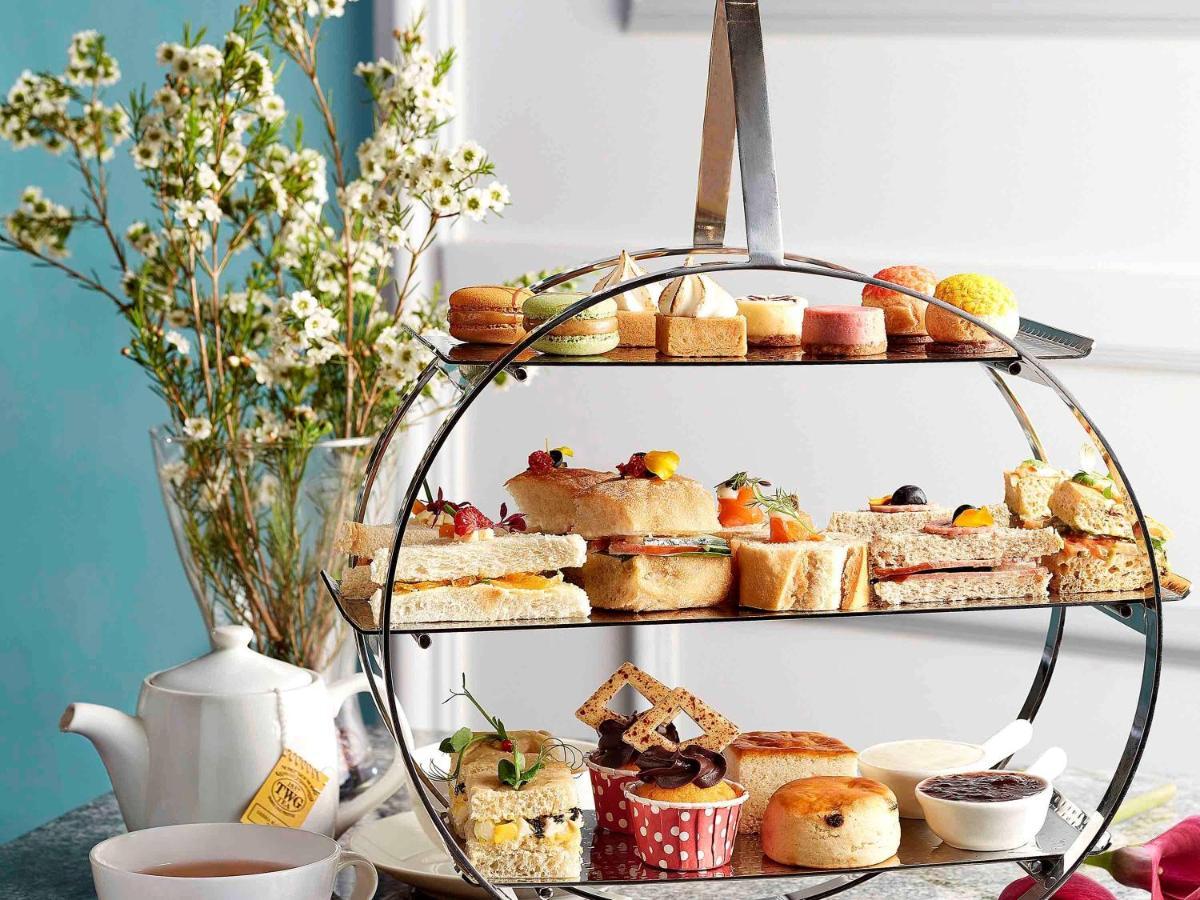 Paradox Singapore Merchant Court At Clarke Quay المظهر الخارجي الصورة The photo features a tiered serving stand filled with an assortment of delightful treats. Each layer displays a variety of items, including sandwiches, pastries, and small cakes. The bottom tier showcases a selection of sweets, such as scones and col