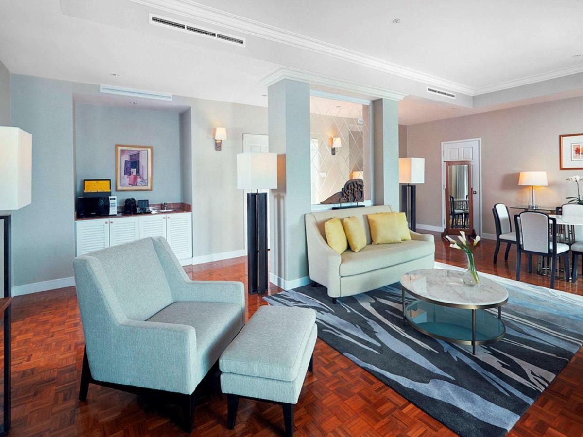 Paradox Singapore Merchant Court At Clarke Quay المظهر الخارجي الصورة The photo shows a modern living space, which includes a seating area with a light-colored sofa that has yellow cushions, and an armchair with an ottoman. A round glass coffee table sits in the center on a patterned rug. In the background, there is a 