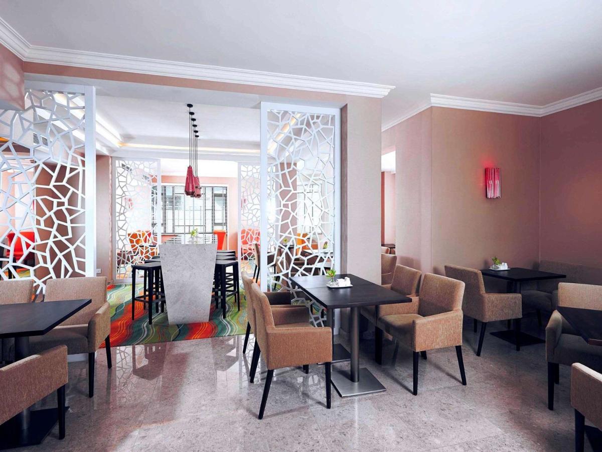 Paradox Singapore Merchant Court At Clarke Quay المظهر الخارجي الصورة The photo shows a modern restaurant interior. There are several tables arranged with dark surfaces and comfortable beige chairs. The walls are painted in neutral tones, and there are decorative partition screens with an abstract pattern that adds a c