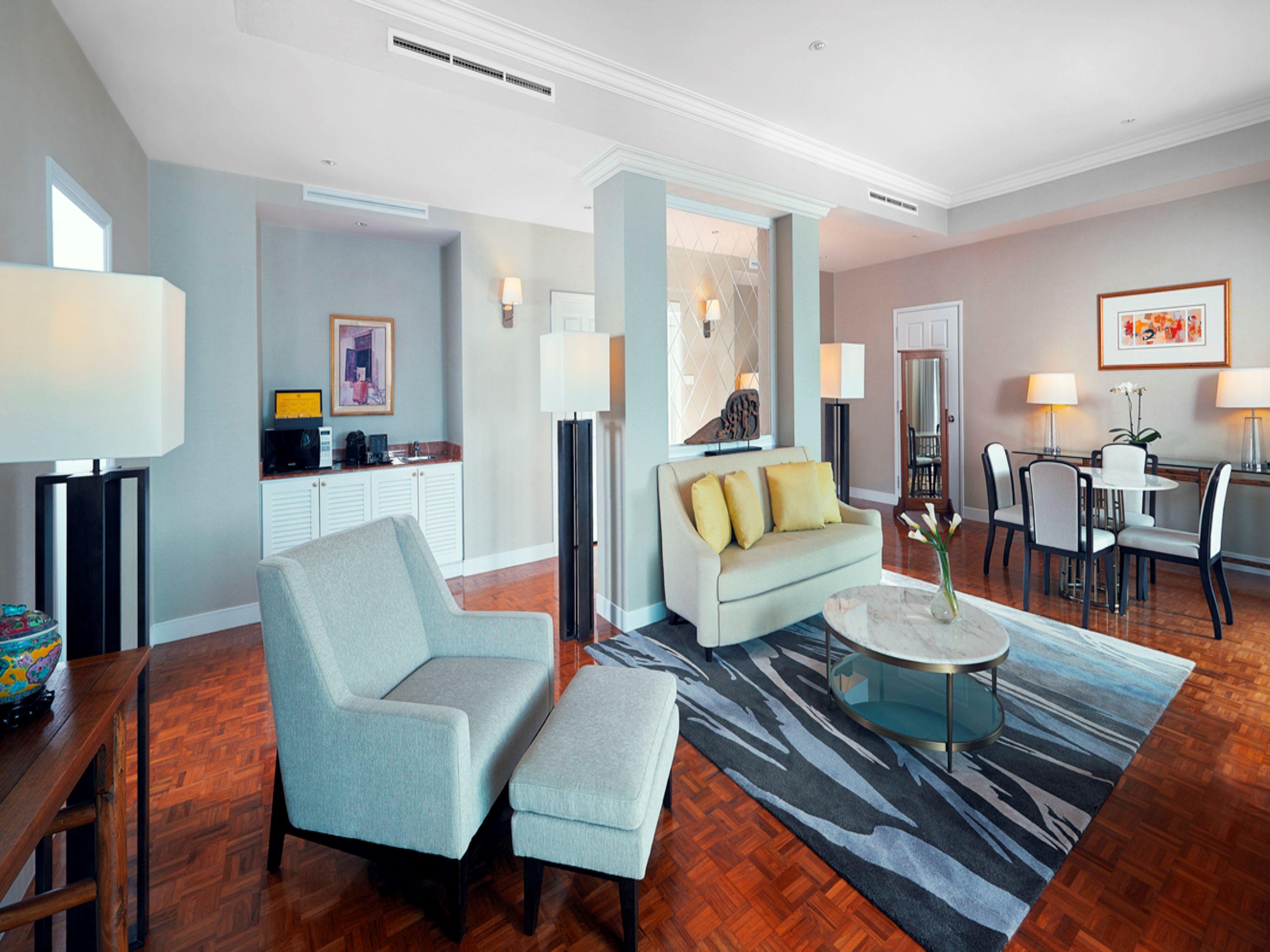 Paradox Singapore Merchant Court At Clarke Quay المظهر الخارجي الصورة The photo shows a modern and stylish living space. It features a pair of light-colored armchairs and a settee with yellow cushions, arranged around a circular glass coffee table. A patterned area rug lies underneath. There are floor lamps providing l