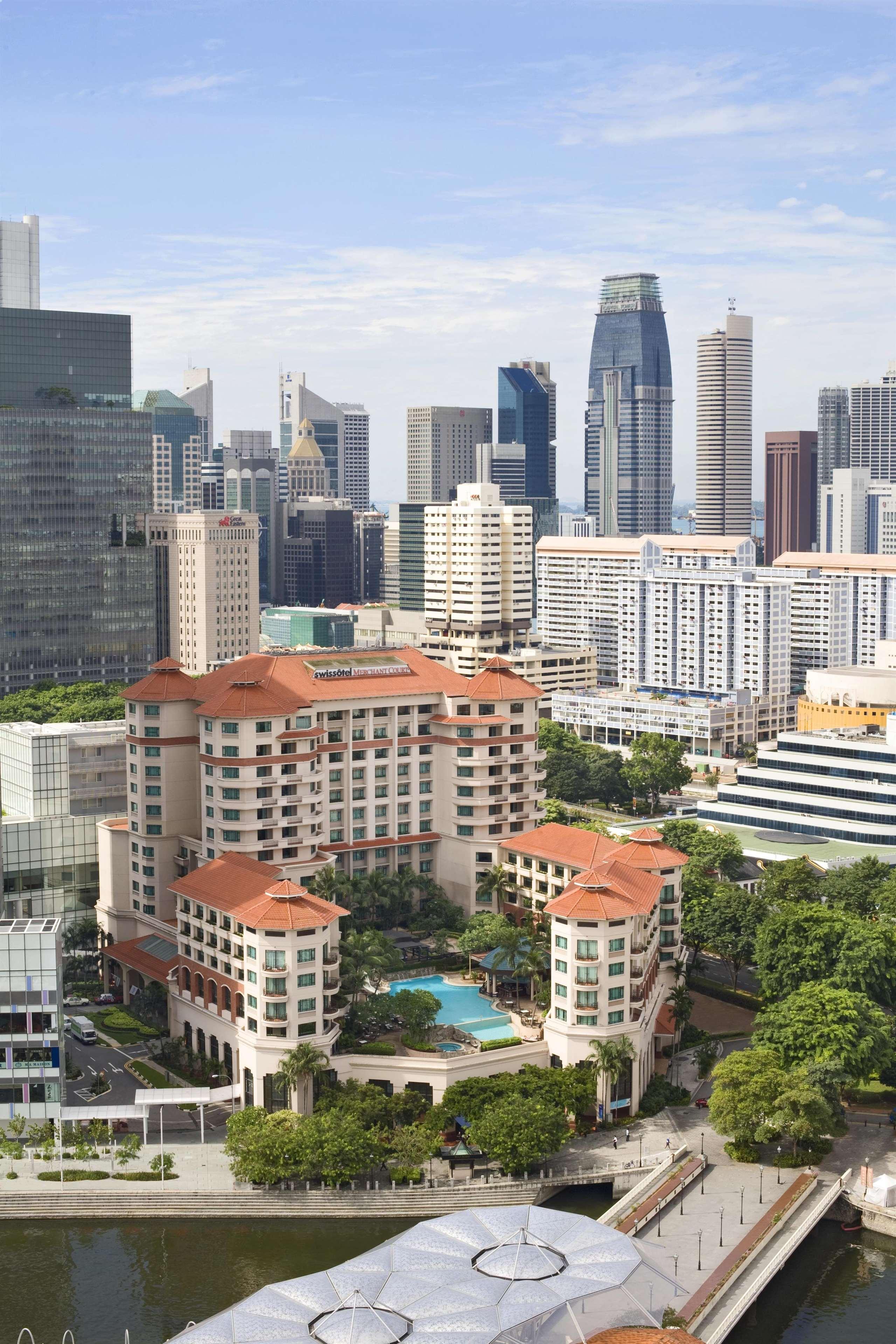 Paradox Singapore Merchant Court At Clarke Quay المظهر الخارجي الصورة The photo shows a cityscape featuring a mix of modern skyscrapers and buildings. In the foreground, there is a large hotel with a distinctive architectural style, characterized by its multi-level structure and a tiled roof. Surrounding the hotel, the