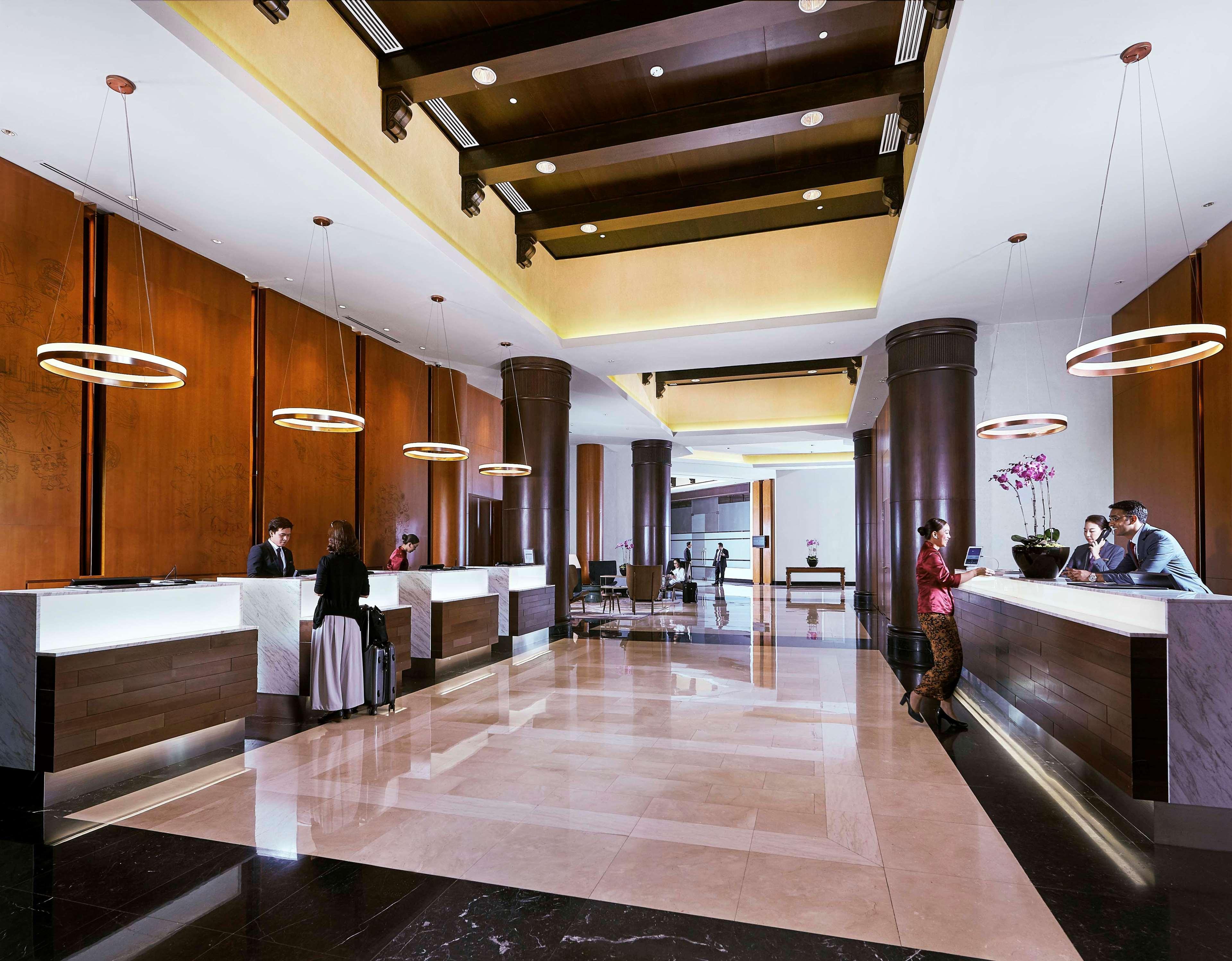 Paradox Singapore Merchant Court At Clarke Quay المظهر الخارجي الصورة The photo depicts a hotel lobby with a modern and elegant design. It features a spacious area with high ceilings, stylish lighting fixtures, and large pillars. There are reception desks on either side, where staff members are attending to guests. The