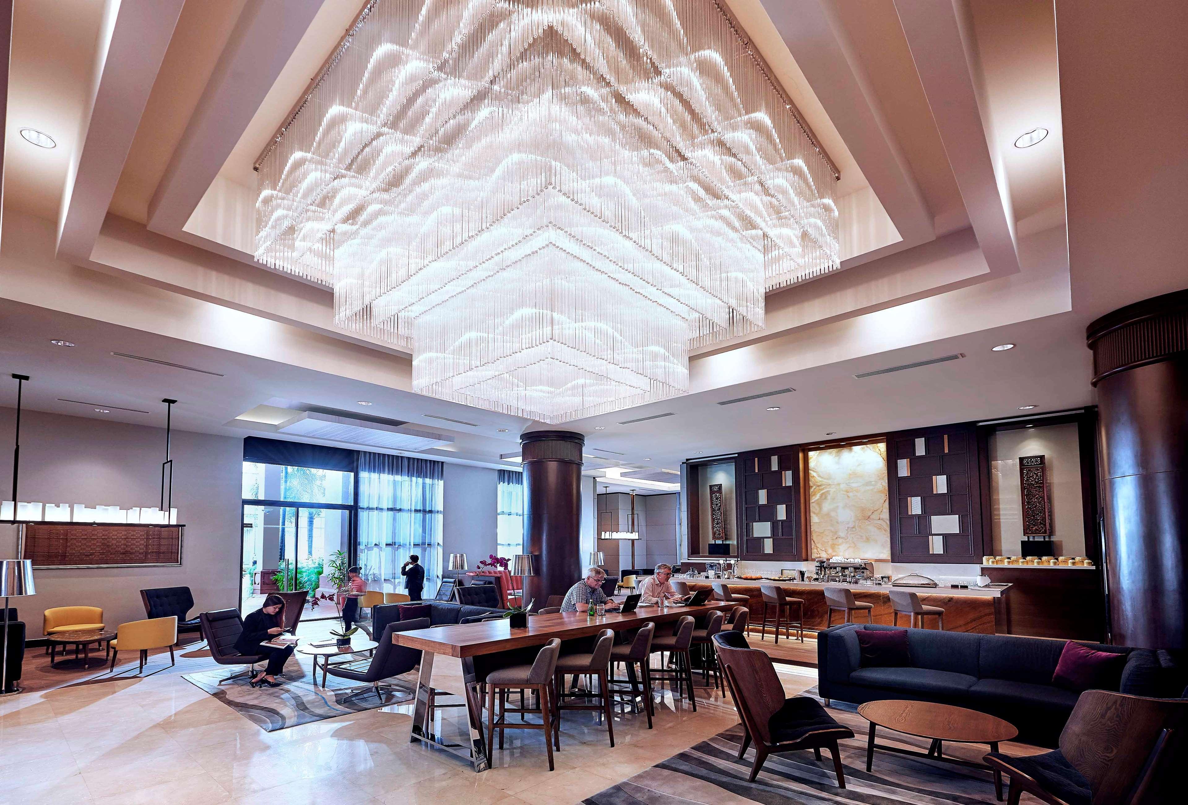 Paradox Singapore Merchant Court At Clarke Quay المظهر الخارجي الصورة The photo shows a modern and stylish interior space, likely a hotel lobby or lounge. A large, intricate chandelier hangs from the ceiling, illuminating the area with soft light. The floor is composed of elegant tiles, and there is a mix of seating ar