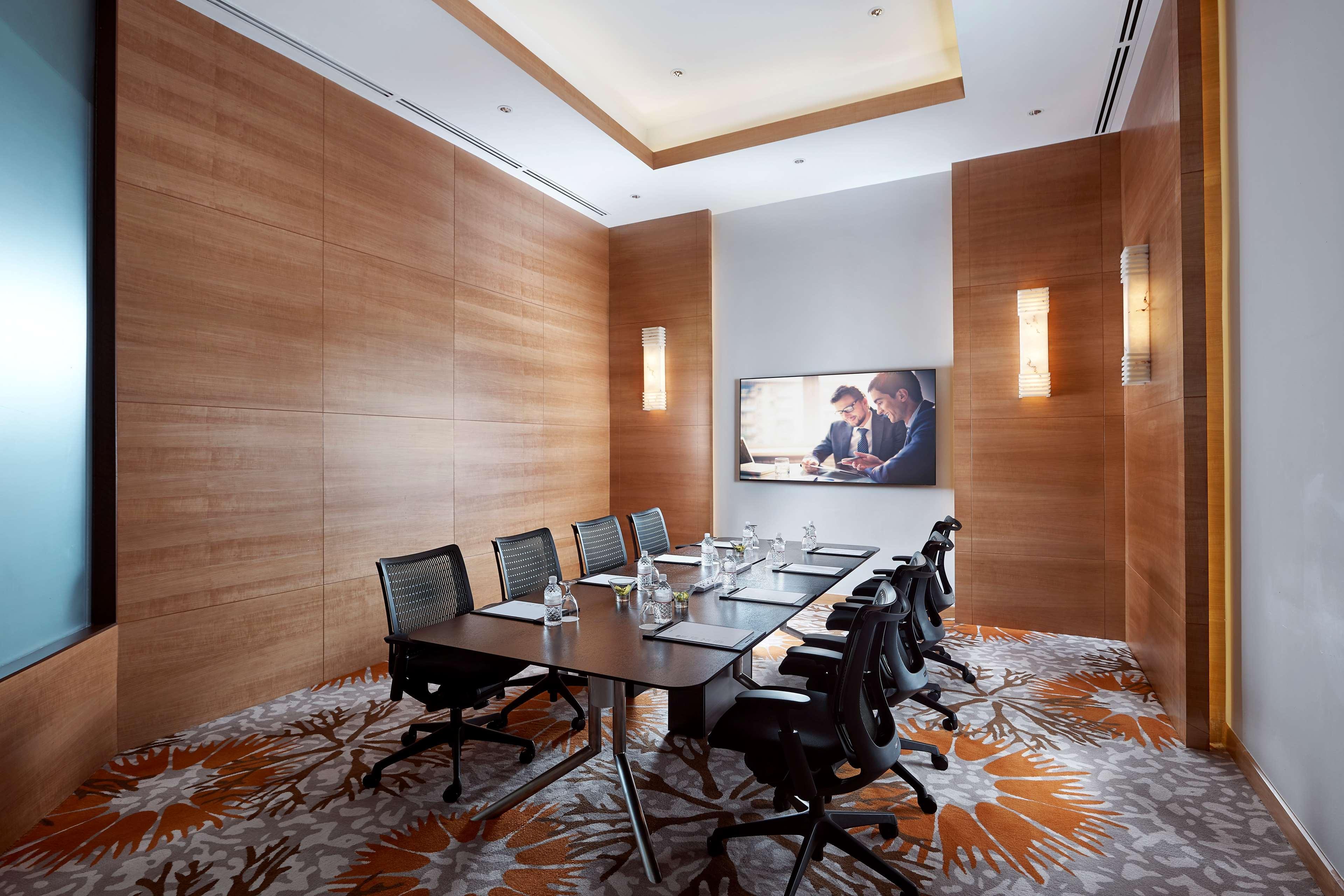 Paradox Singapore Merchant Court At Clarke Quay المظهر الخارجي الصورة The photo shows a modern conference room featuring a large wooden table surrounded by several black office chairs. The room has wooden paneling on the walls, creating a warm ambiance. There's a large screen mounted on one wall, likely for presentatio