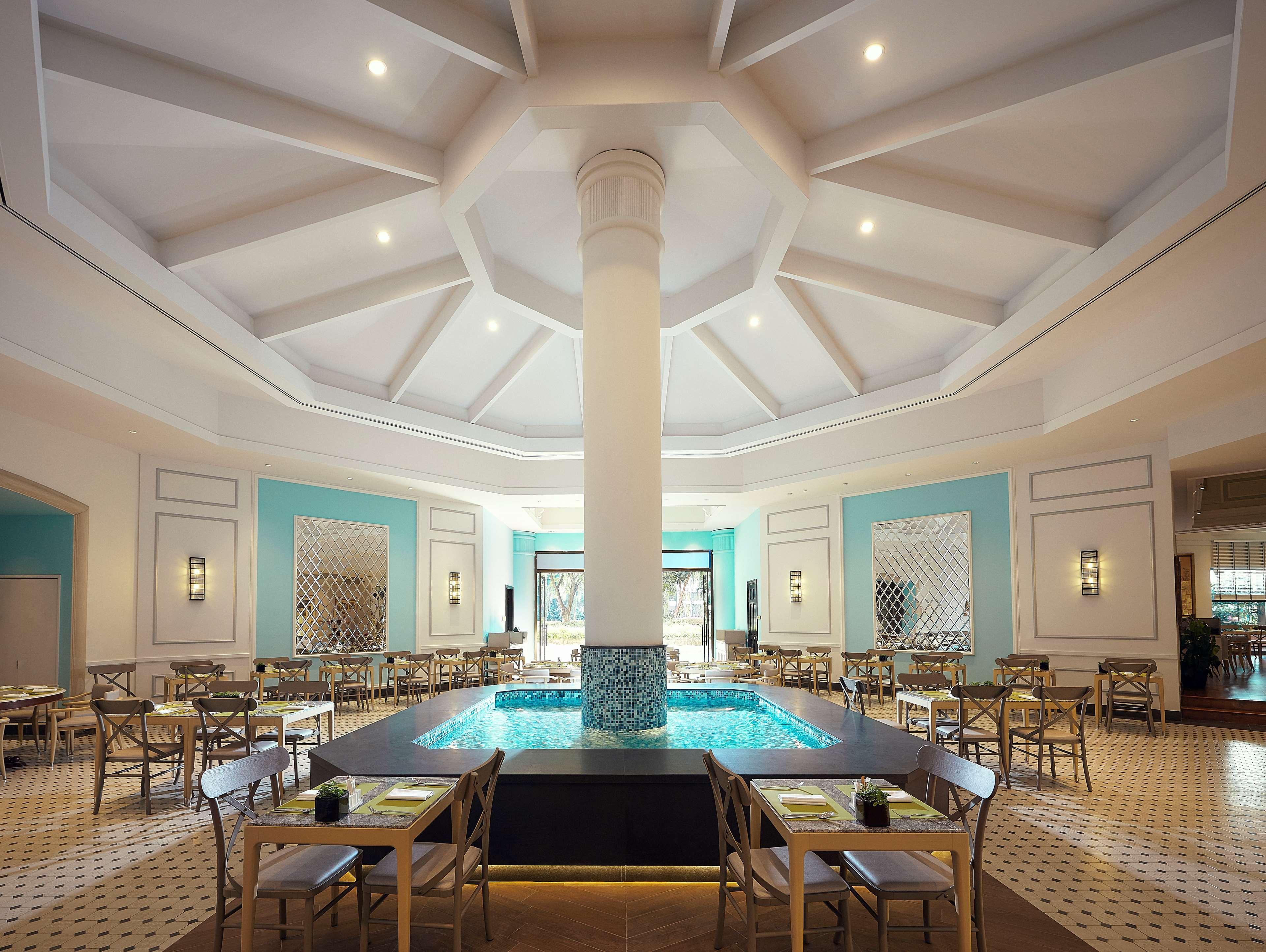 Paradox Singapore Merchant Court At Clarke Quay المظهر الخارجي الصورة The photo shows an elegant dining area with a spacious, open layout. There is a large column in the center, surrounded by a circular water feature that adds a serene atmosphere. The ceiling is designed with a geometric pattern, giving it a modern loo