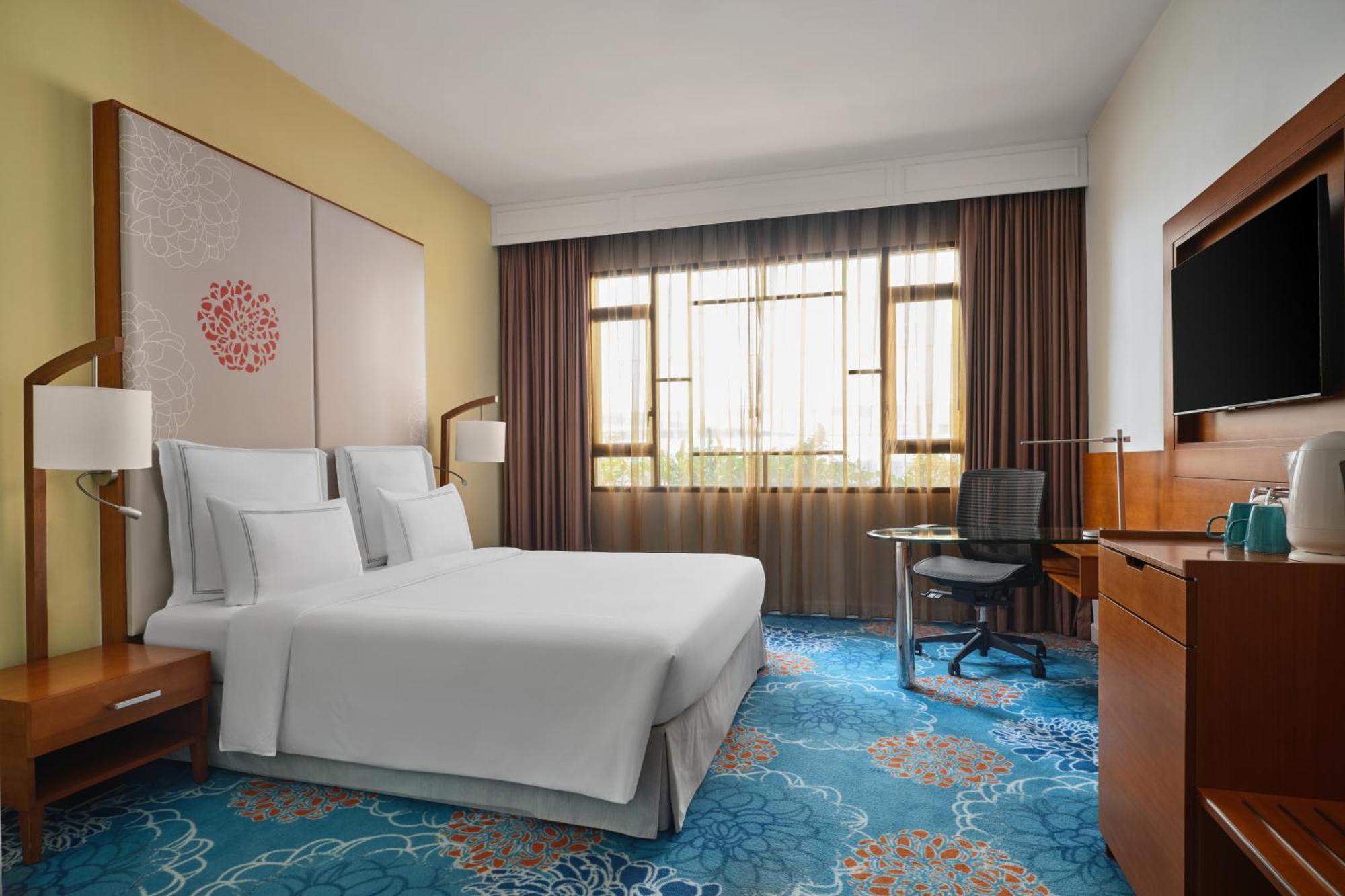 Paradox Singapore Merchant Court At Clarke Quay المظهر الخارجي الصورة The photo shows a hotel room featuring a modern and inviting design. It includes a bed with white linens, two bedside lamps, and a decorative wall behind the bed. There is a large window covered with sheer and dark curtains, allowing natural light to