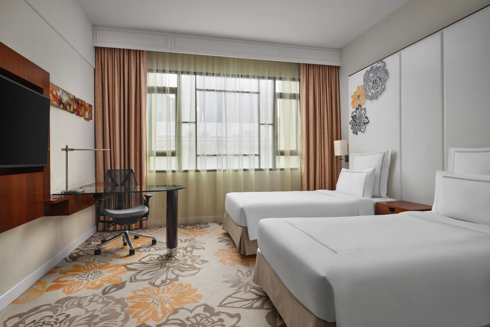 Paradox Singapore Merchant Court At Clarke Quay المظهر الخارجي الصورة The photo shows a modern hotel room featuring two twin beds with white bedding. There is a large window with sheer curtains allowing natural light to fill the space. In the corner, there's a stylish desk with an ergonomic chair. The room has a light 
